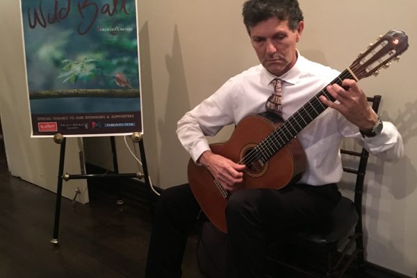 Classical guitarist Angelo Sartorelli entertains guests who are arriving.